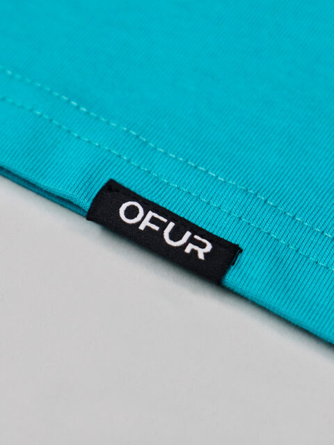 Close up of the OFUR hem label on the green T-Shirt