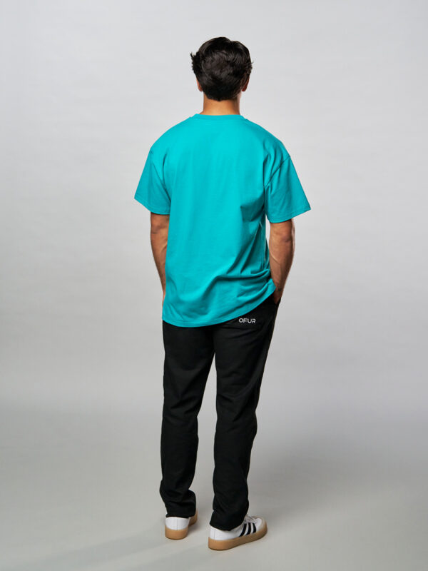 Model seen from behind with the original magenta green T-Shirt in combination with the OFUR black pants