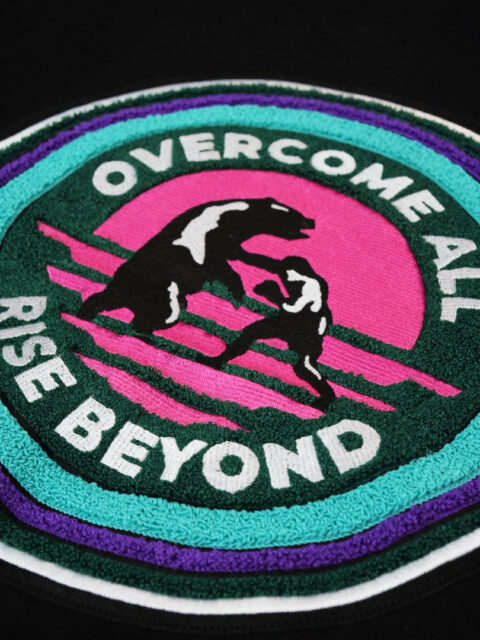 Backprint of the rise beyond varsity jacket with the text overcome all rise beyond
