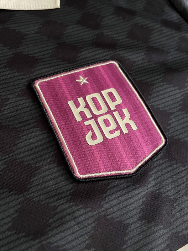 Close up of the chest-patch of the KOPJEK logo on the KOPJEK X OFUR – 15TH ANNIVERSARY FOOTBALL JERSEY