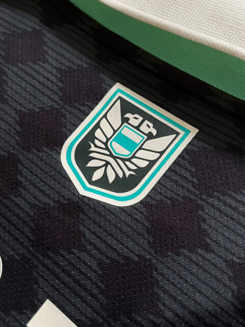 Close up of the neck logo in the KOPJEK X OFUR – 15TH ANNIVERSARY FOOTBALL JERSEY